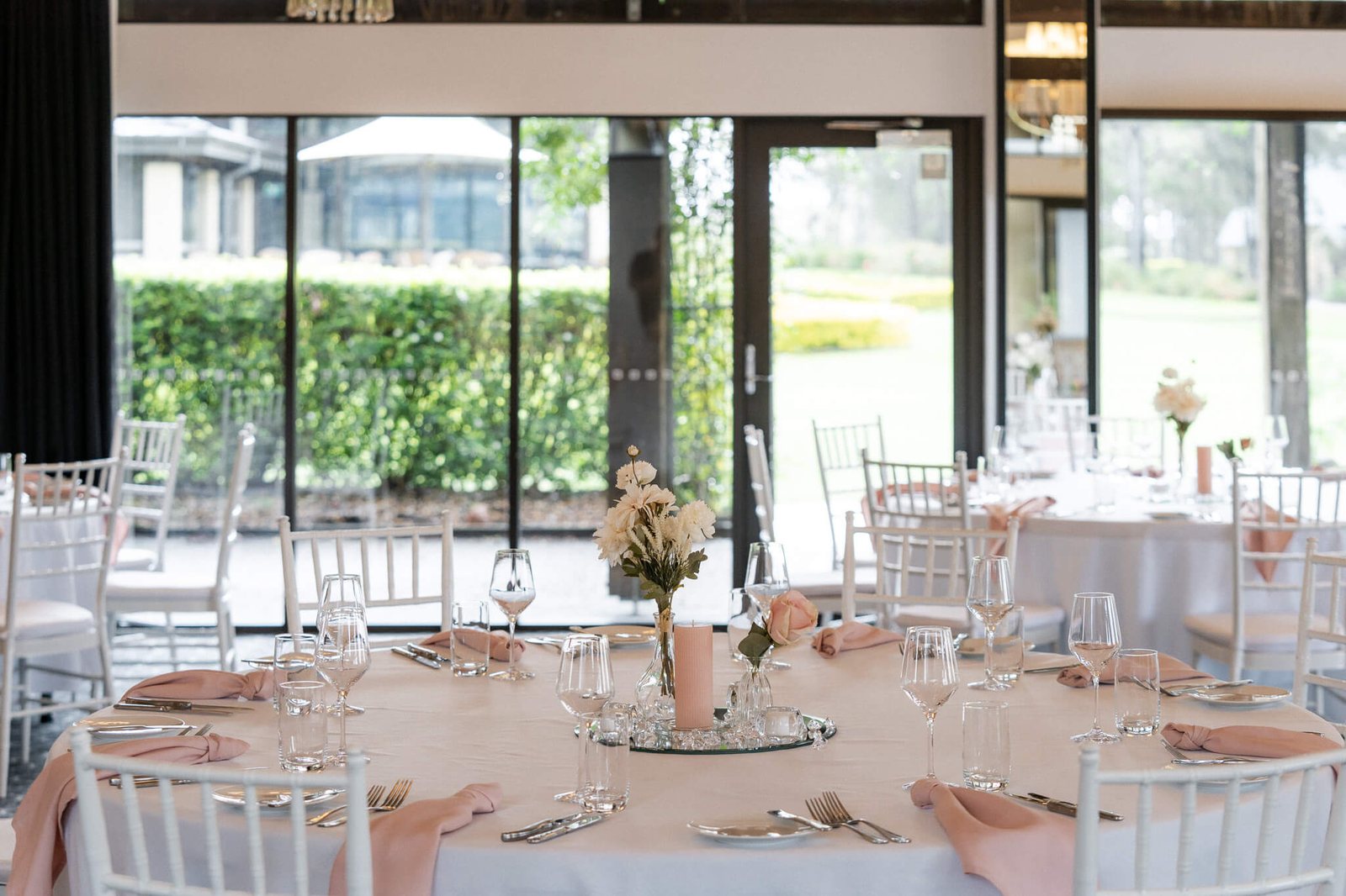 Round tables with florals in the Barrington Room, windows to the course