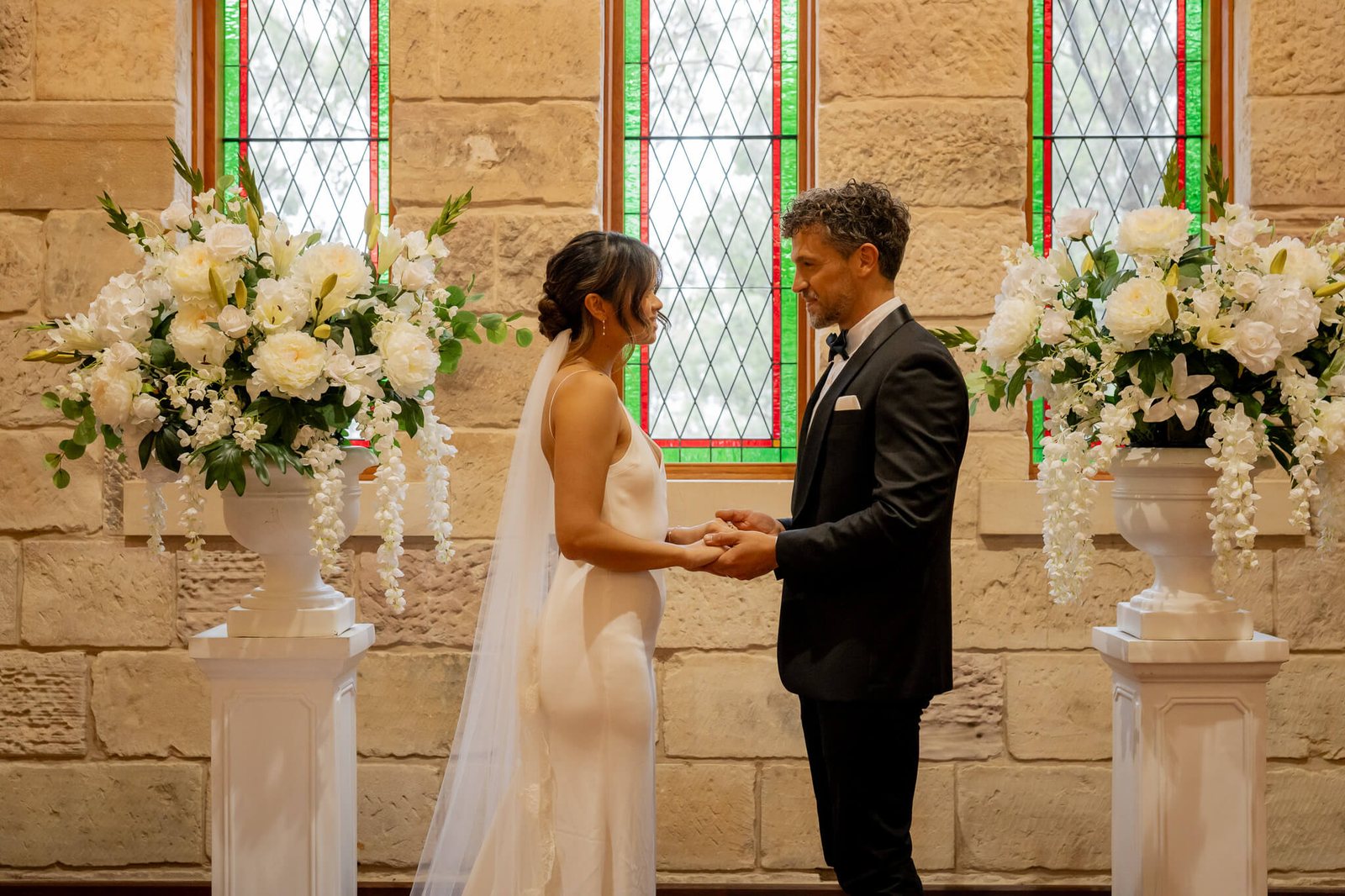 A ceremony at the altar of the Carriage House, white florals and stained glass